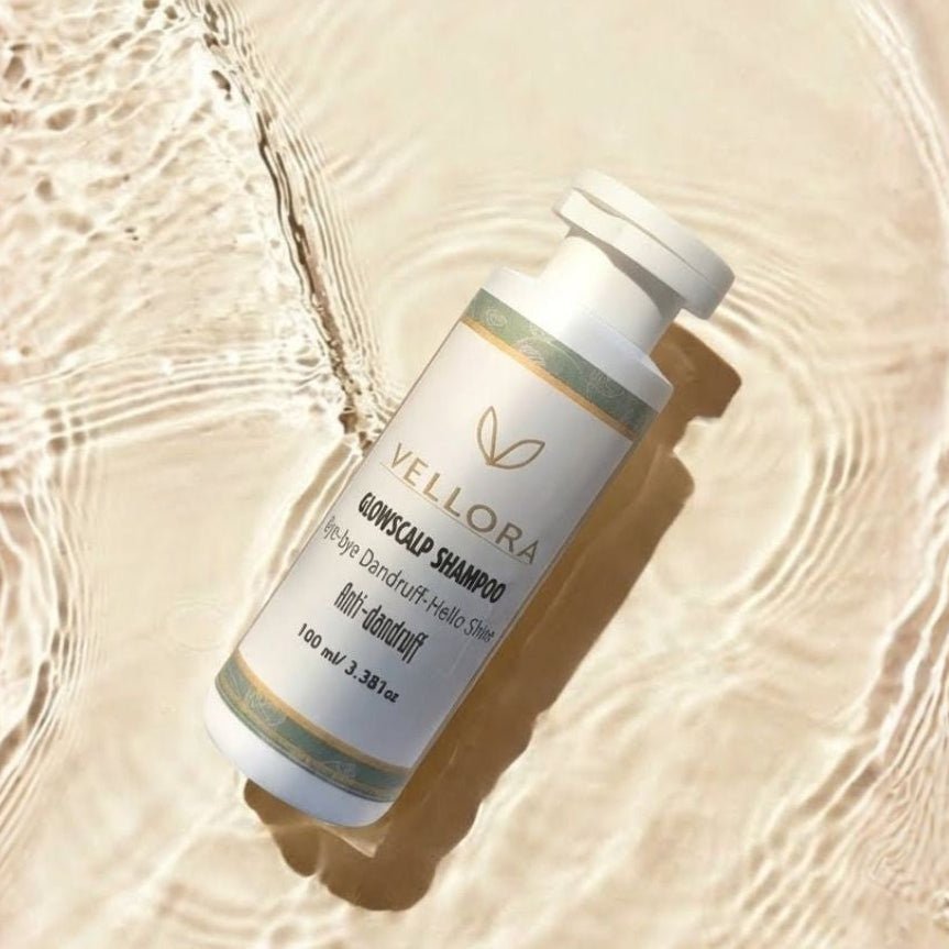 Vellora Glowscalp Anti-Dandruff Shampoo bottle on water ripple background, scalp care shampoo to fight dandruff, reduce flakes and add healthy shine for clean, refreshed hair.